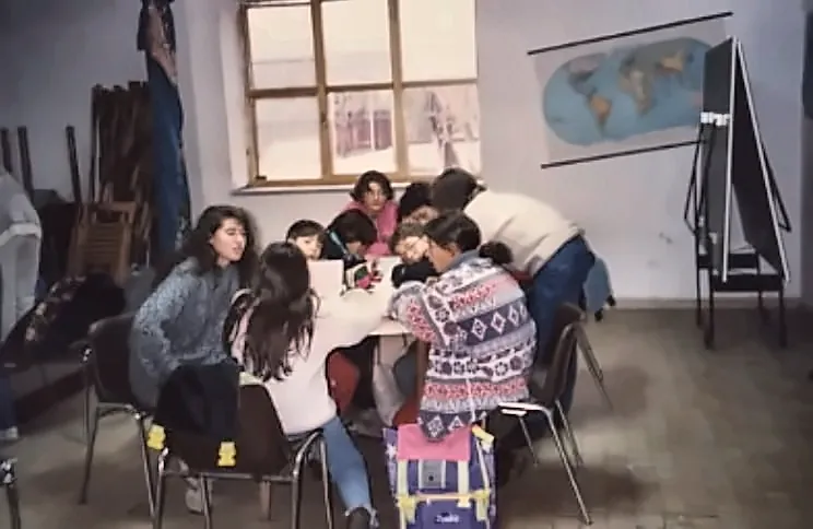Ragazzi e volontarie intorno al tavolo del doposcuola