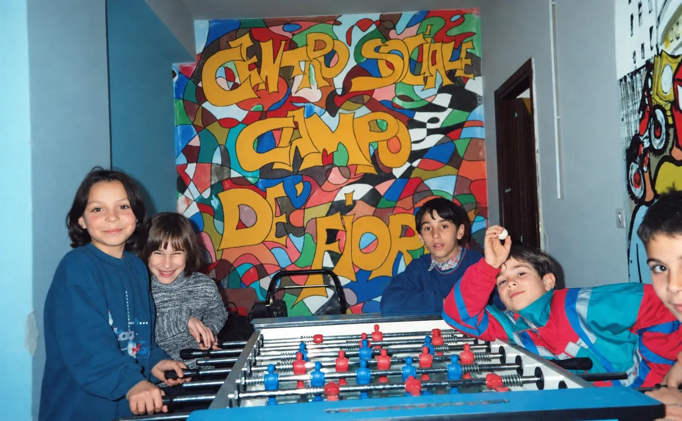 Bambini al biliardino davanti al grande murale «Centro Sociale Campo dei Fiori»