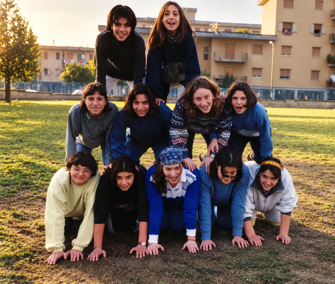 Ragazze in piramide sul prato, con i palazzi del rione Gescal sullo sfondo