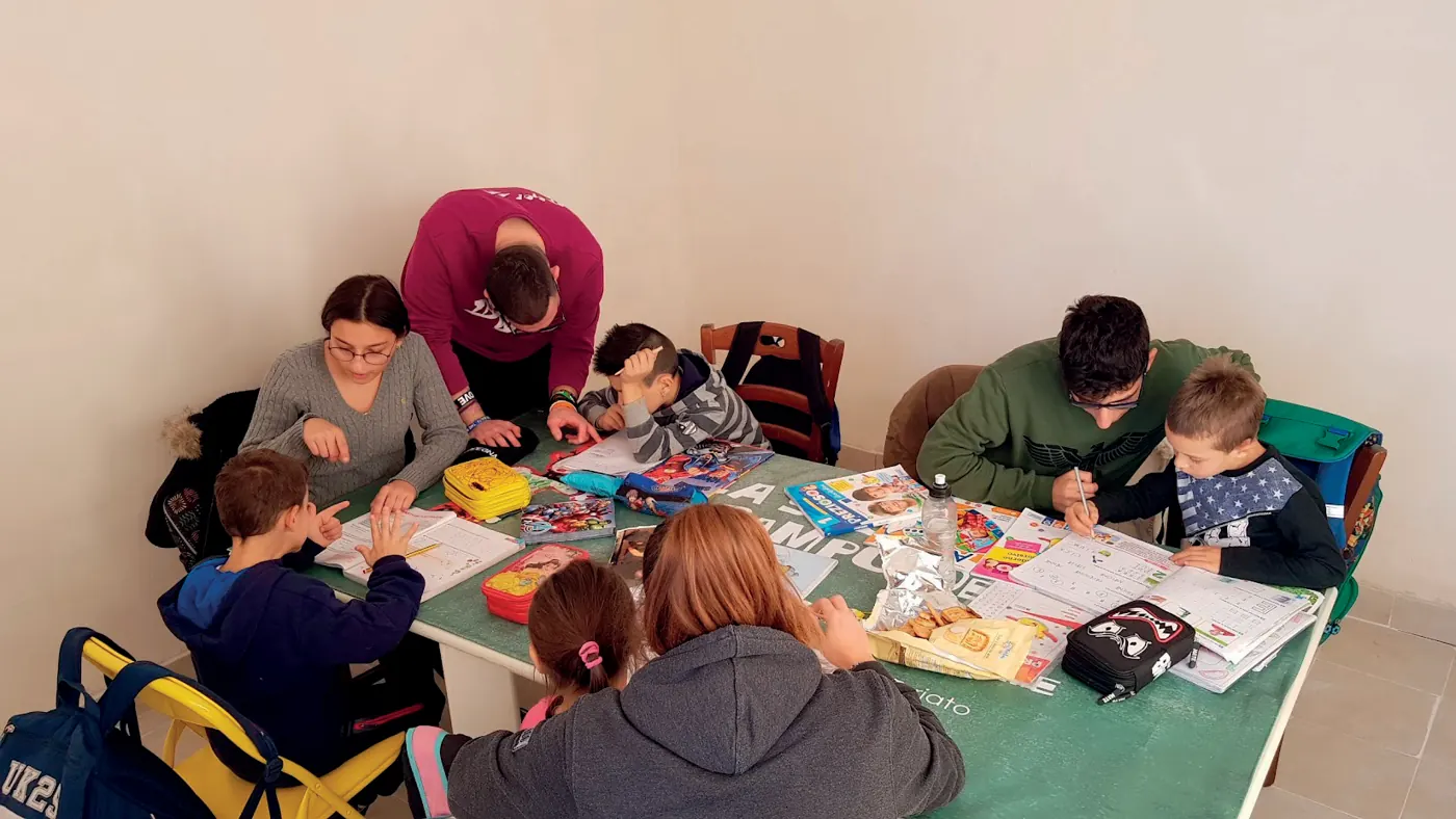 Bambini e volontari al tavolo del doposcuola
